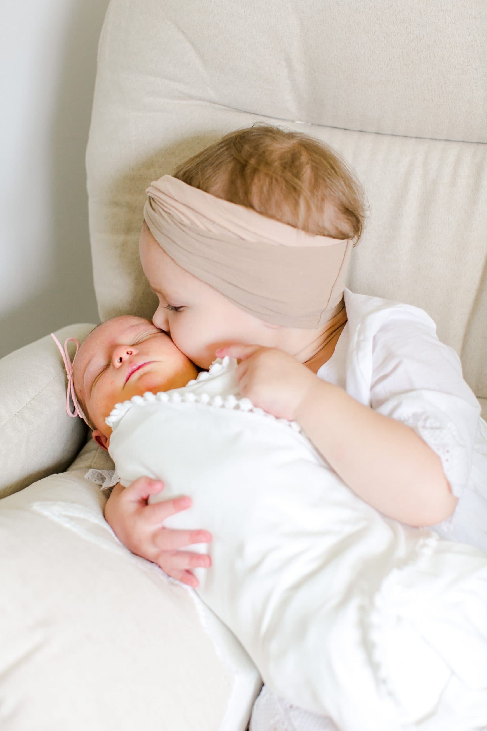 Baby and big sisters snuggling during newborn photo shoot