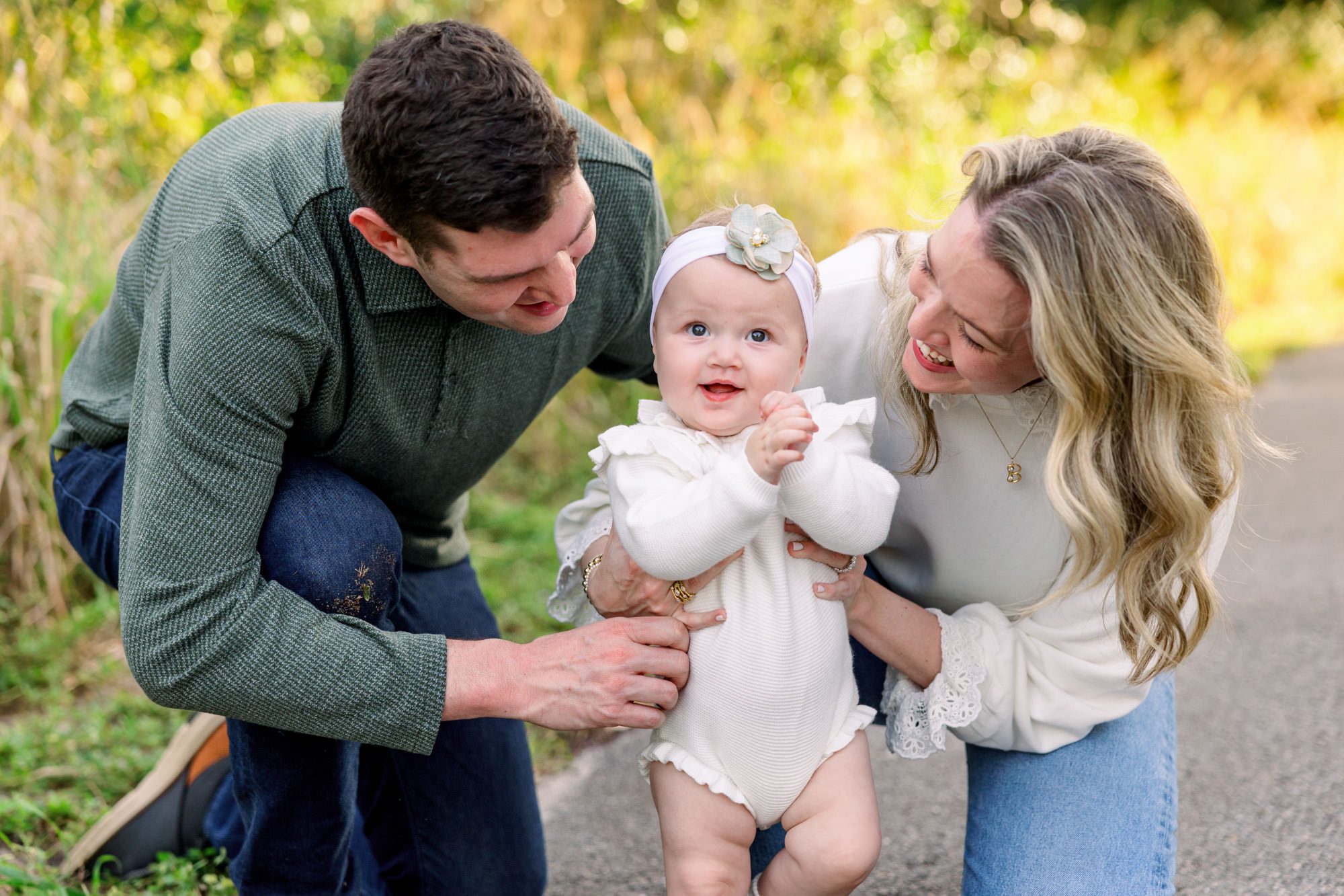 Toddler girl smiling while parents hold her