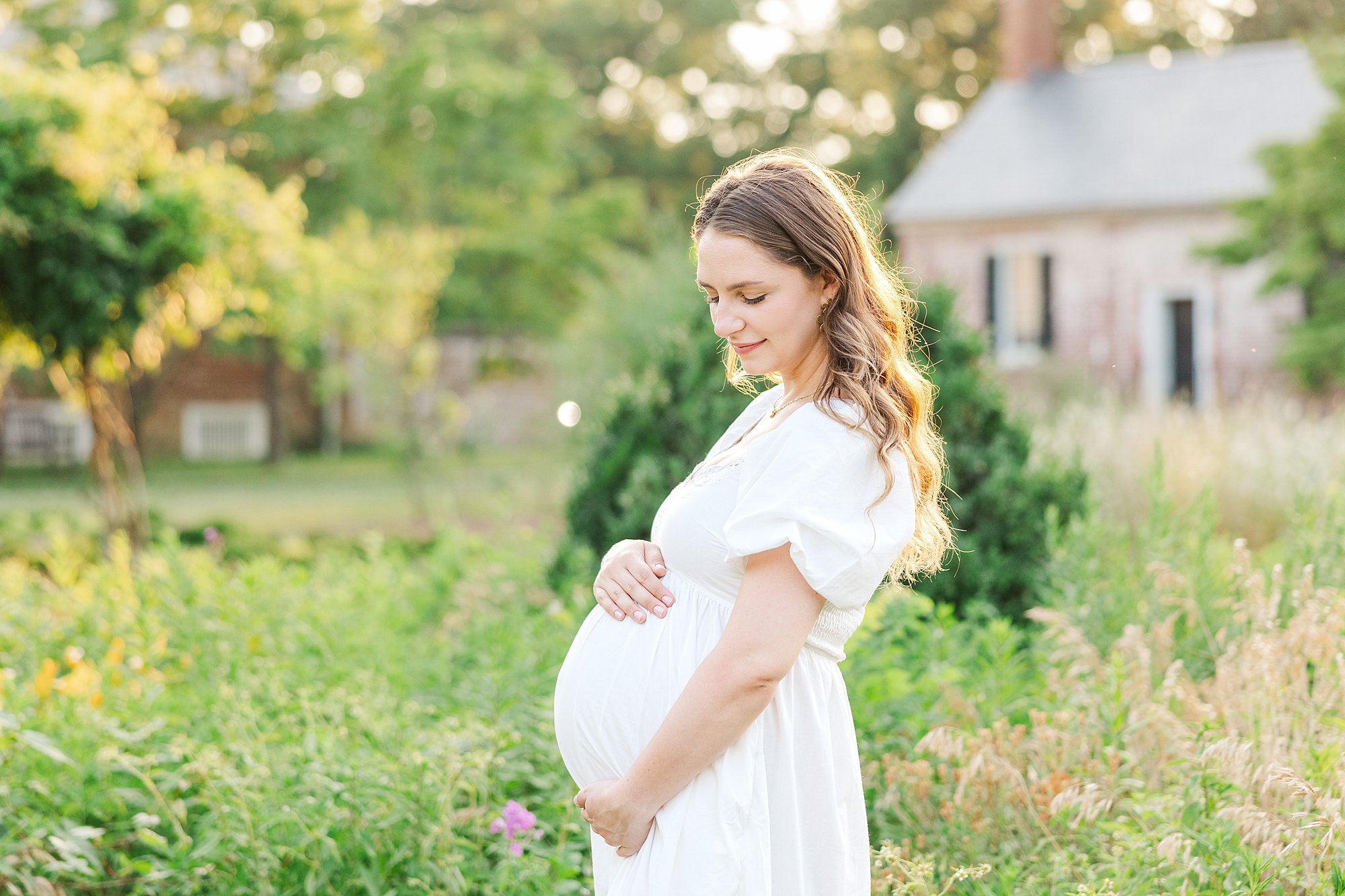 Outdoor Fredericksburg VA maternity session with mom wearing white dress in a garden