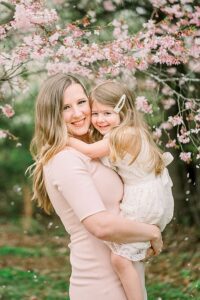 Mom in pink dress holding daughter in white dress as example for spring family photos outfit ideas